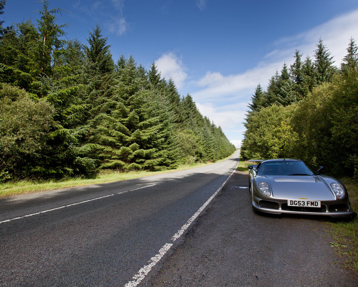 A sports car parked on a tree-lined UK B-road