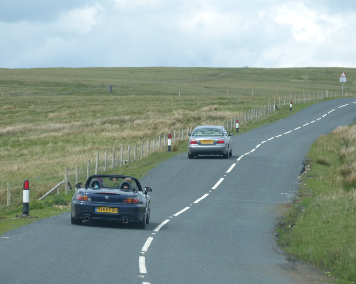 A sports car driving on an open UK countryside road